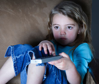 Child Sitting On The Couch Holding Remote and Watching TV