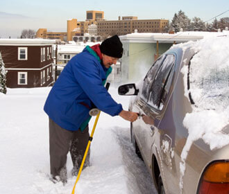 Man shoveling snow from around car