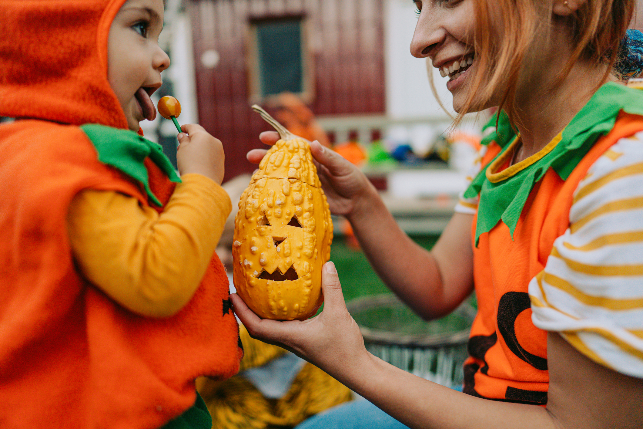 Mom handing a pumpkin to a kid eating candy