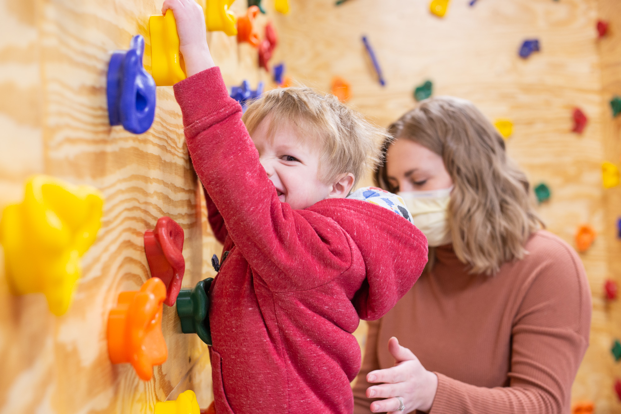 Occupational Therapist Alyssa Lucas, MS, OTR/L, celebrates with a patient after success on St. Luke’s in-house pediatric climbing wall.