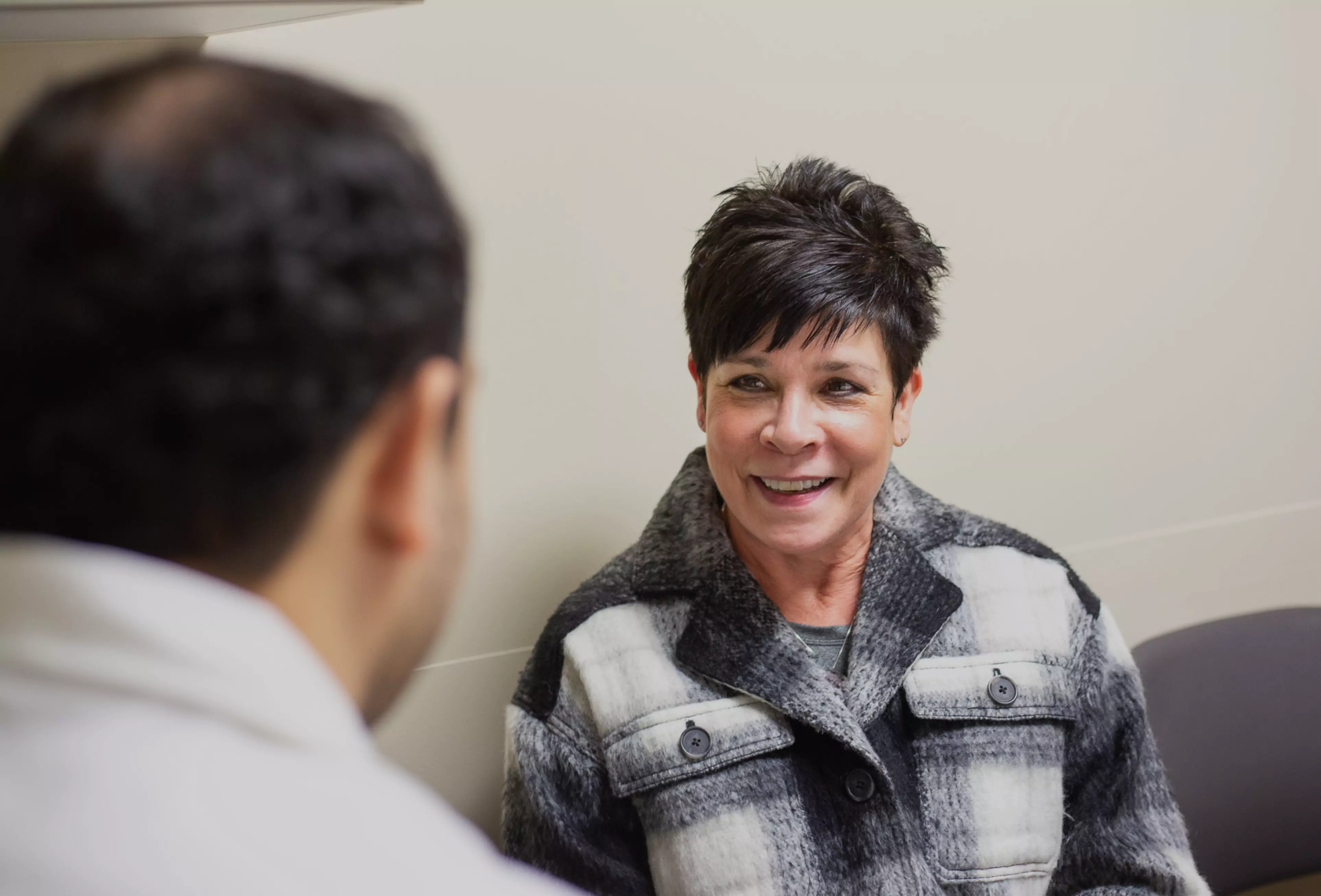 middle aged woman smiles at her primary care provider while they talk