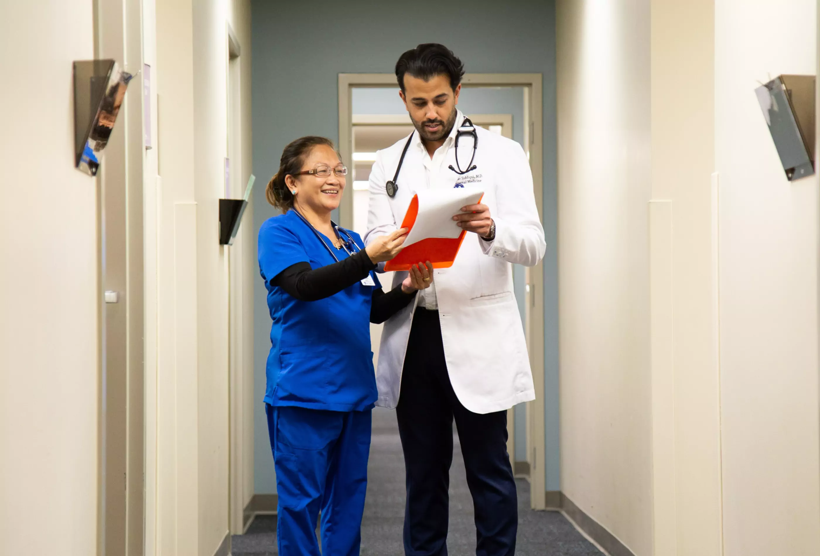 An internal medicine doctor and medical assistant looking at a patient's chart together.