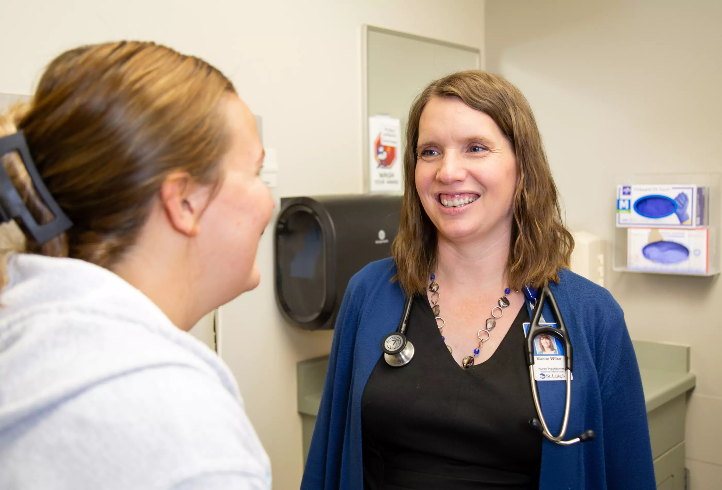 An internal medicine nurse practitioner smiling at a young female patient.