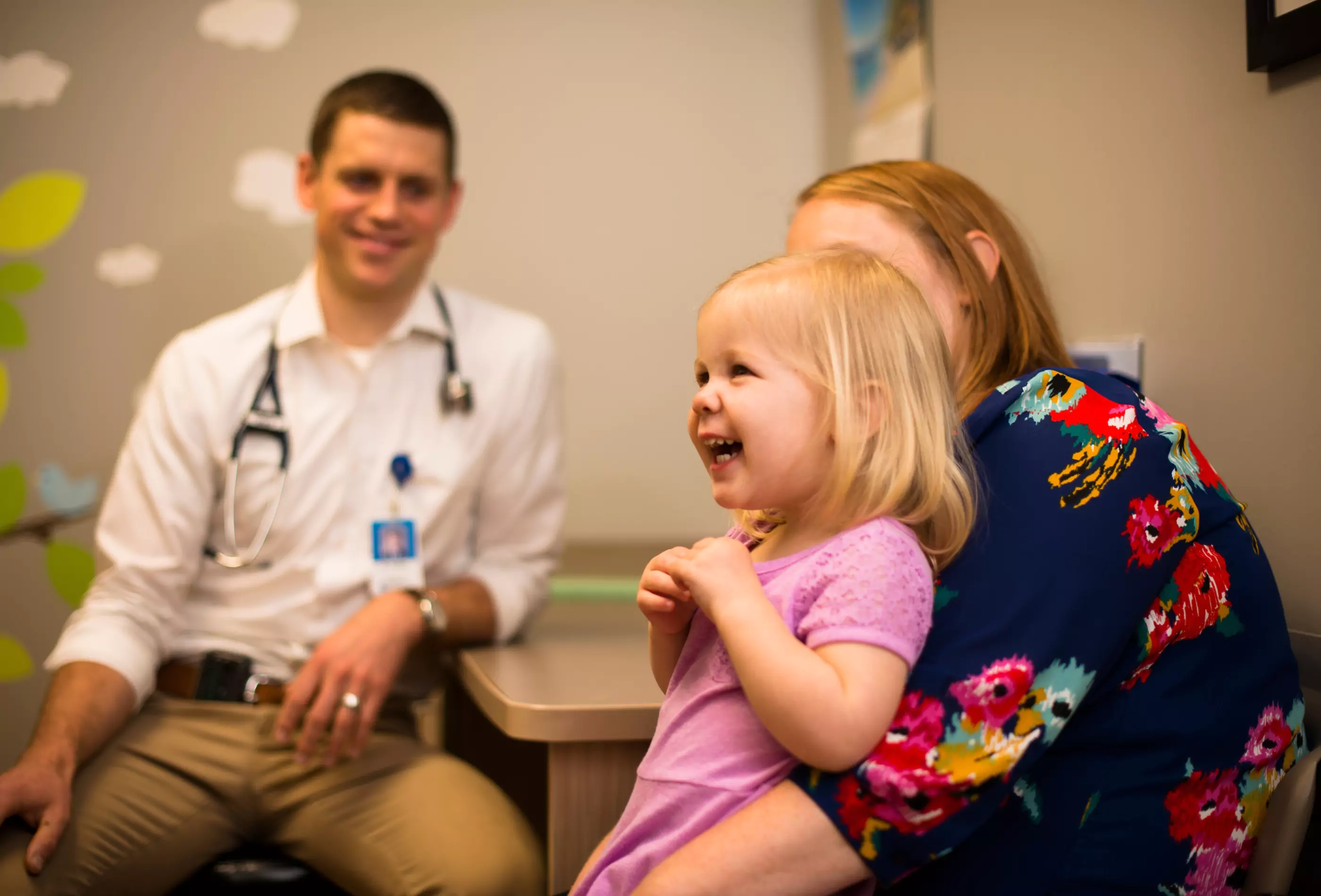 Kid laughing with Mom while having a wellness exam.