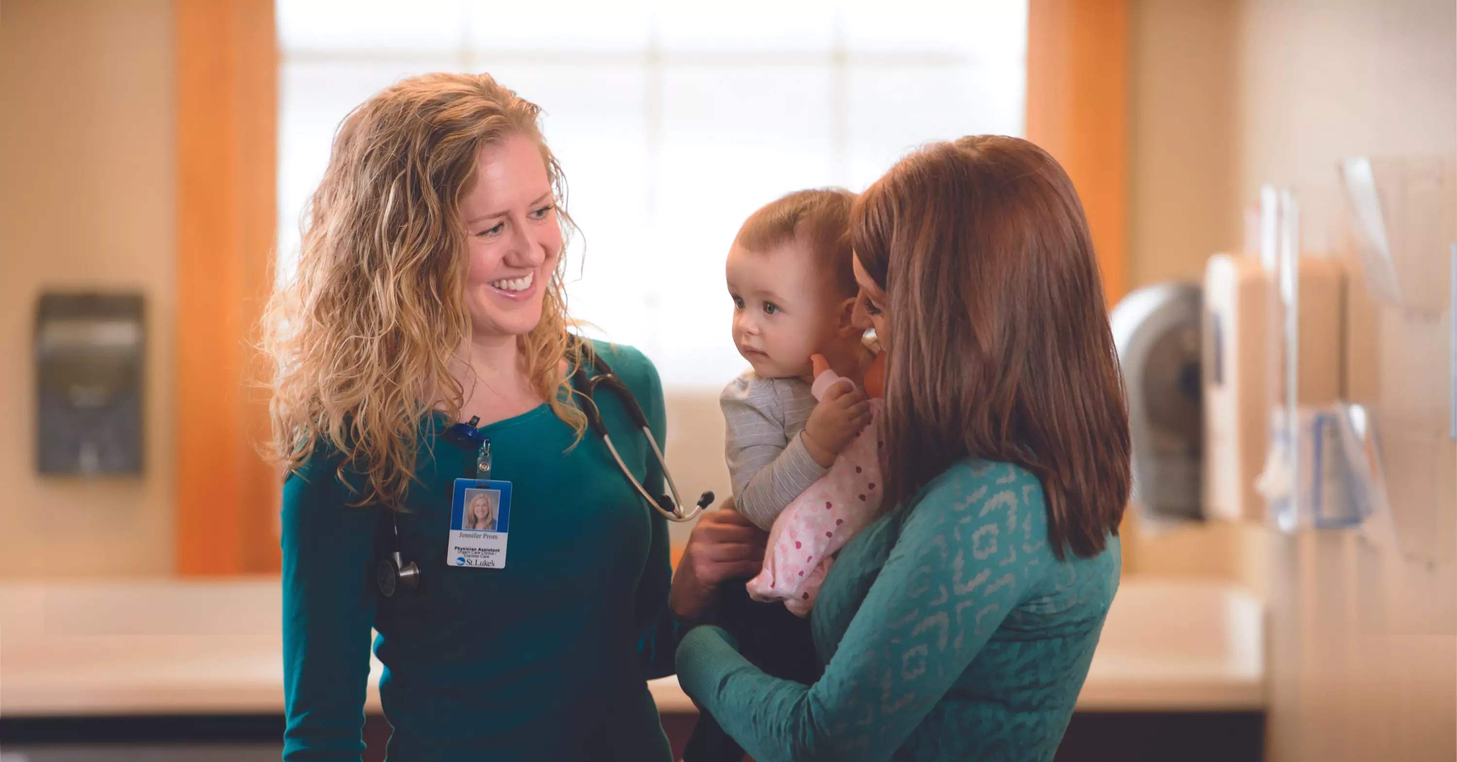 St. Luke's provider smiling at mother and child.