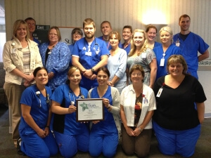 Staff Holding Award In A Group Photo